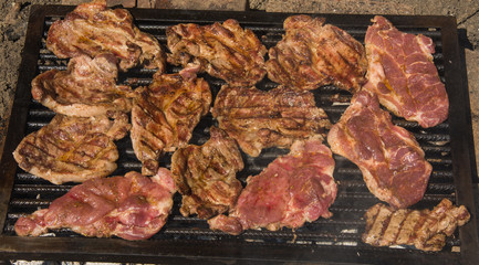 Grilling pork steaks on barbecue grill