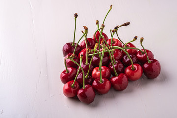 Obraz na płótnie Canvas Cherry berries with stem on wooden white background and water drops