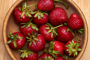 Close-up fresh strawberry in wooden bowl isolated on wooden background.