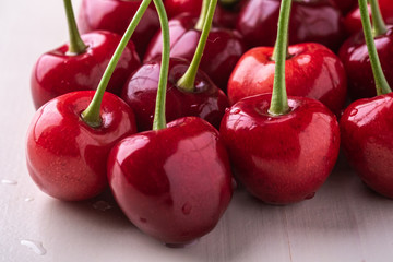 Cherry berries with stem on wooden white background and water drops