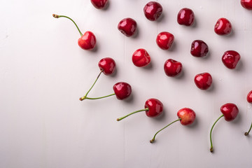 Fototapeta na wymiar Copy space cherry berries with stem on wooden white background and water drops top view