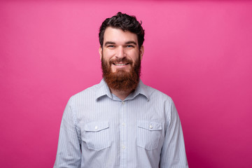 Obraz premium Portrait of smiling young bearded man in casual standing over pink background