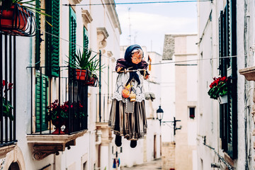 Locorotondo, Italy - March 9, 2019: Ancient ritual with witch-shaped dolls are suspended high across the streets of the Italian city of Locorotondo, on Easter, the witches are burned.