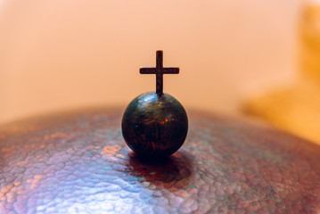 Christian cross on a small metal ball, negative space.