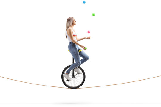 Young woman riding a unicycle on a rope and juggling with balls