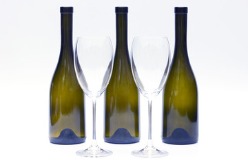 Three empty upturned wine bottles and two glasses on a white background