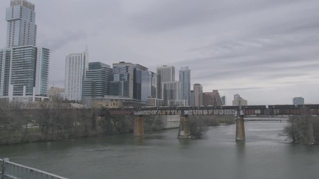 a freight train crosses the Colorardo River and heads into downtown Austin