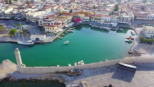 Aerial drone video of unique old picturesque Venetian port with old lighthouse in the heart of famous city of Rethymno at sunset, Crete island, Greec