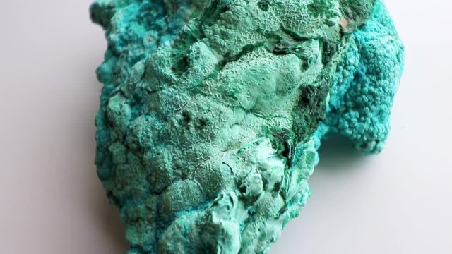 Panning, rear view of a beautiful blue and green mineral called Chrysocolla, against a white background.