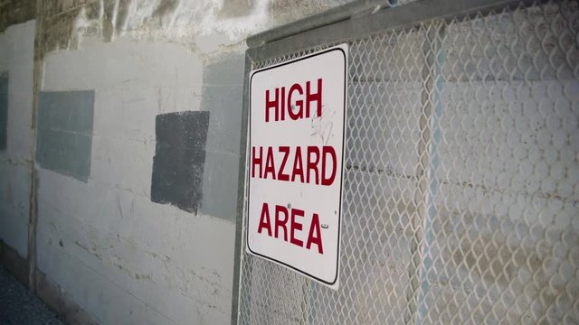 High Hazard Sign posted on a gate leading into a cement tunnel