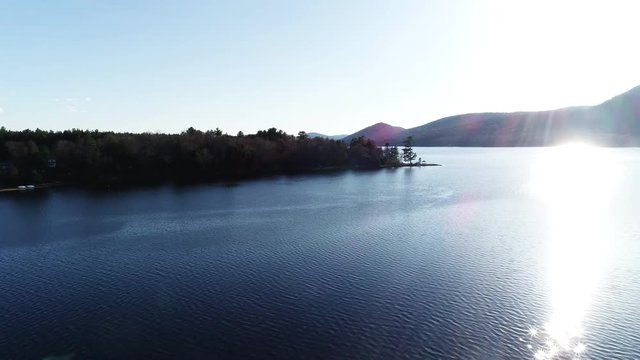 Wide aerial sun shines over lake in Adirondack Mountains