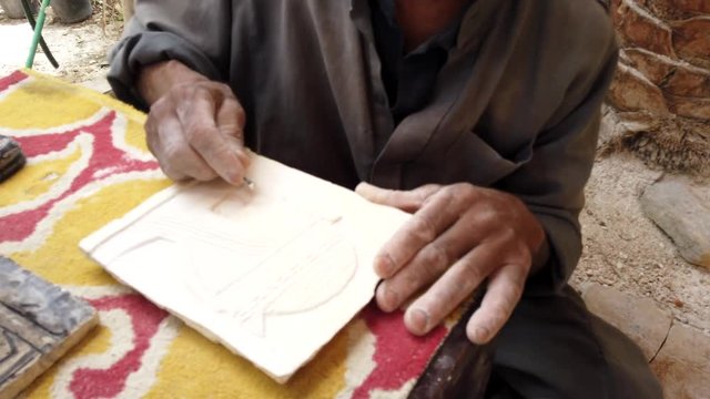 Man Carves Pattern Onto Clay Tablet For Decoration.