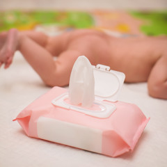 close up wet napkin. daily children's hygiene. newborn lying on his stomach in selective focus on the background