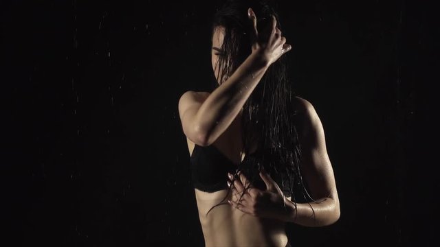 Young woman touching her skin in slow motion on black