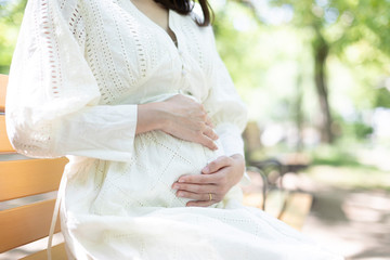 公園のベンチに座るに妊婦