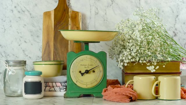 Vintage kitchen scale decor, and farmhouse style kitchenware with gypsophila flowers against a white marble background.