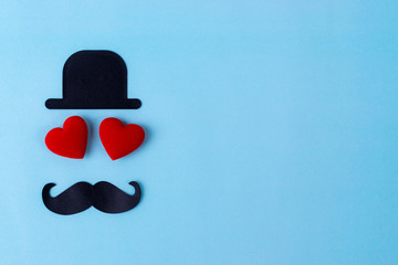Happy Father's day background or card. Black sign of hat, mustache and two red heart - eyes with pale blue background and copy space for text.