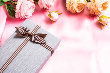 Beautiful gift box with roses on a pink fabric background