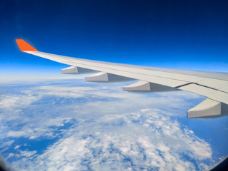 Fototapeta na wymiar During the morning journey view of wing of an airplane from window seat overlooking clouds and sky 