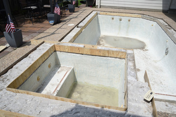 Empty swimming pool under remodel with wooden forms for new tile and coping and concrete