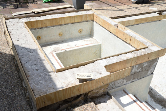 Empty swimming pool under remodel with wooden forms for new tile and coping and concrete