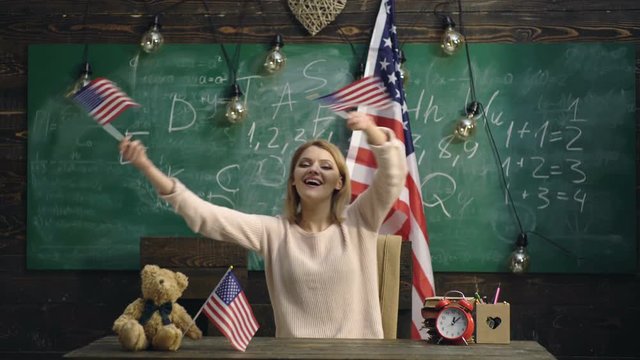 Woman waving US flags. School background. Happy patriotic woman holding USA flag while siting isolated over green board background. Patriotism and freedom. Independence day of usa. Background. - Powered by Adobe