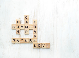 crossword wooden letter. theme of summer, vacation, travel. crossword made from wooden letters block on white wooden background. Minimalism style, copy space, top view.