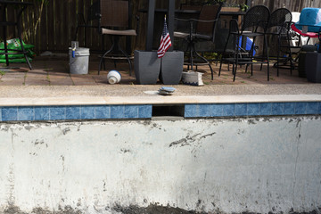 Empty swimming pool remodel with new tile and coping with American flag in background