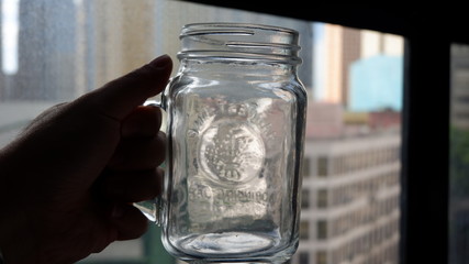 Hand holding a transparent empty drinking jar