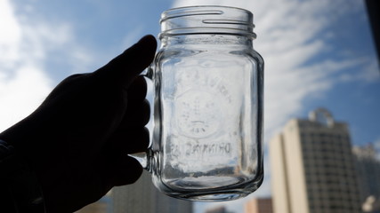 Hand holding a transparent empty drinking jar