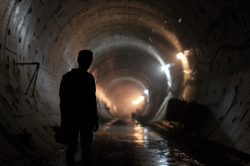Silhouette of a lonely male builder in the Moscow metro tunnel