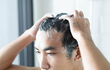 Closeup young man washing hair with with shampoo in the bathroom, health care concept, selective...