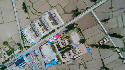 Aerial view of poor small village with school in the middle of dry farm land during hot summer season , Gansu, China