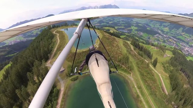 Hang glider pilot speeds up over lake in famous Kitzbuhel ski resort in summer 