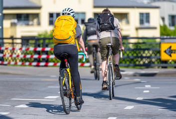 Fototapeta na wymiar Convoy of amateur cyclists crosses pedestrian crossing at crossroad on the bikes