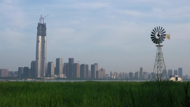 Multi-bladed windpump in middle of Hankou marshland and Wuhan city skyline in background in Hubei China