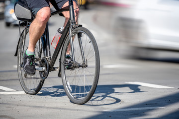 Fototapeta na wymiar Male cyclist in shorts rides bike along city street next to other traffic