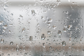 Close up of rain water droplets on glass window at high-rise condominium during rainy season in Bangkok