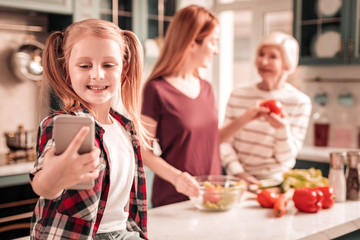 Positive delighted kid doing selfie photo on telephone