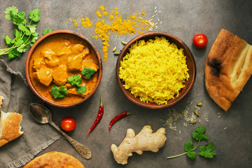 Chicken tikka masala spicy curry meat food , rice and naan bread on a brown rustic background. Indian and UK dish. Top view, copy space, flat lay.