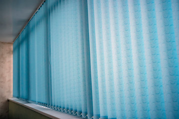 Blue vertical blinds on the long window on balcony. Modern interior design. Closed window from...
