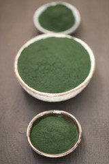 Spirulina algae. dry powder in round cups set on a black table.organic spirulina algae powder.Super food concept.nutritional supplement.