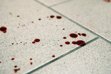 Conceptual image with blood on it resting on tiles on floor
