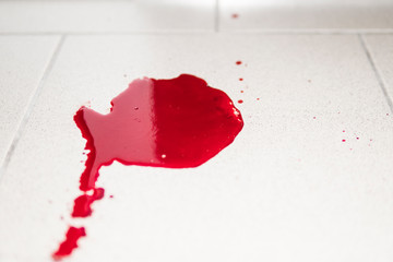 Conceptual image with blood on it resting on tiles on floor. A puddle of dried blood on the tiled...