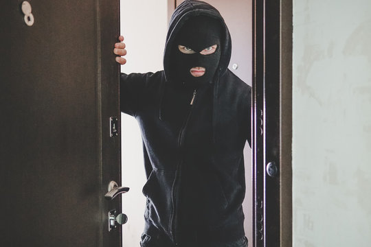 thug keeps the front door Maniac broke into the room. dangerous guest. thief broke down the door. The evil look of the bandit on the camera.