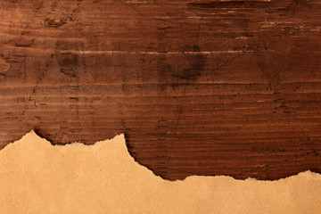 Ripped brown kraft paper, shot from the top on a dark rustic wooden background, a grunge design template with a place for text