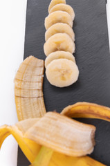 Banana - Pealed and Sliced on a black chopping board, selective focus