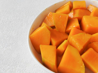 High angle view of a plate of fresh yellow diced mango isolated on white background. Mango is a common fruit in Taiwan during the summer. Summer, fruit, agriculture concept. With copy space.