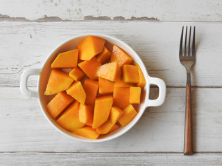 Top view of a plate of fresh yellow diced mango isolated on wooden background, fork beside. Mango is a common fruit in Taiwan during the summer. Summer, fruit, agriculture concept.