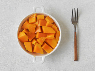 Top view of a plate of fresh yellow diced mango isolated on white background, fork beside. Mango is a common fruit in Taiwan during the summer. With copy space. Summer, fruit, and agriculture concept.
